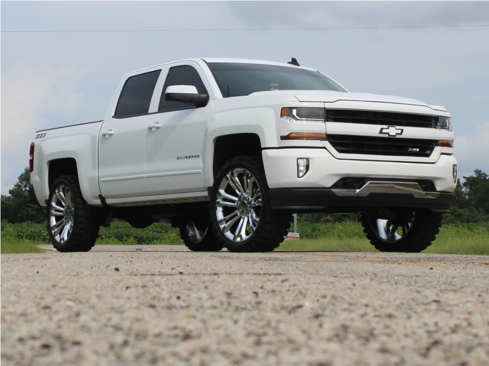 A white 2018 Chevrolet Silverado 1500 running Factory Reproductions Fr55 24x10 +31 wrapped in the Gladiator Xcomp Mt 35